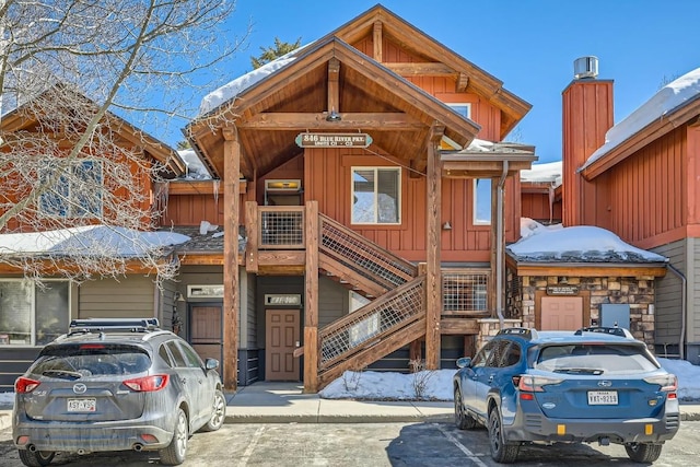 snow covered property with stairway