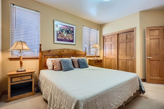 bedroom featuring a closet, light carpet, and baseboards