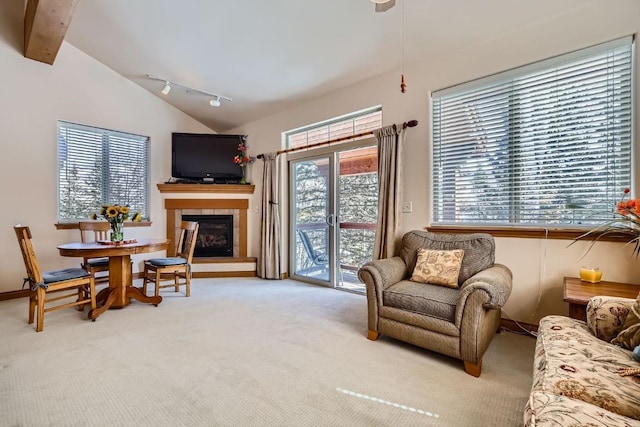 living area featuring lofted ceiling with beams, carpet flooring, and a tiled fireplace