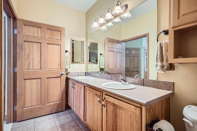 full bath featuring double vanity, tile patterned floors, toilet, and a sink