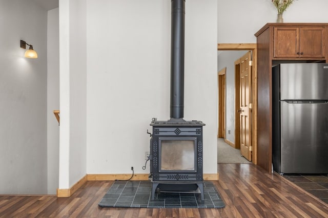 interior details featuring hardwood / wood-style floors, stainless steel refrigerator, and a wood stove