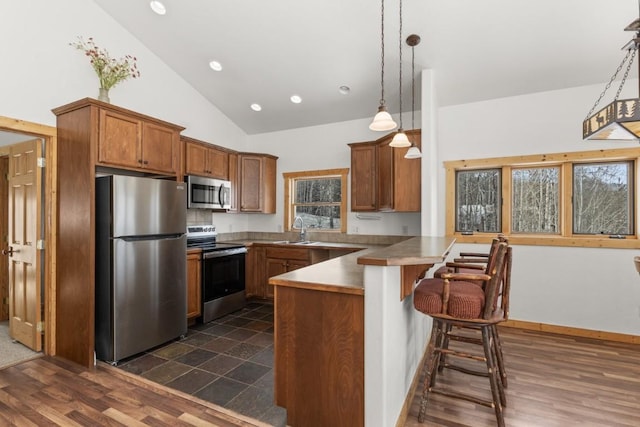 kitchen with a breakfast bar, sink, kitchen peninsula, pendant lighting, and stainless steel appliances