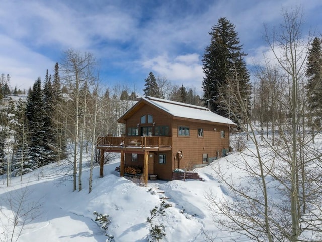 snow covered back of property with a wooden deck