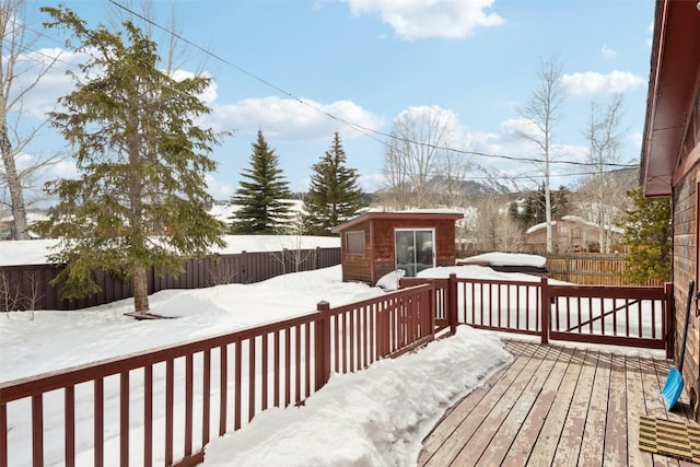 snow covered deck with an outdoor structure and a fenced backyard