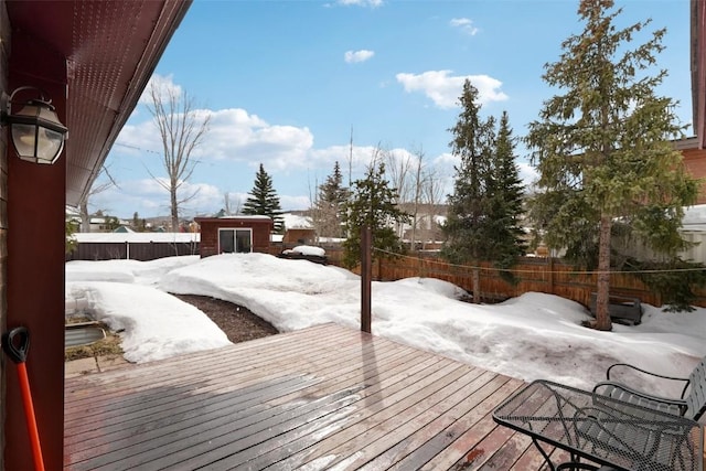 snow covered deck featuring an outbuilding and fence