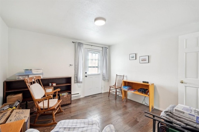 living area with wood finished floors, baseboards, and baseboard heating