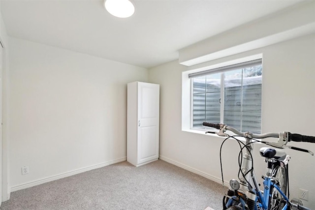 exercise room with light colored carpet and baseboards