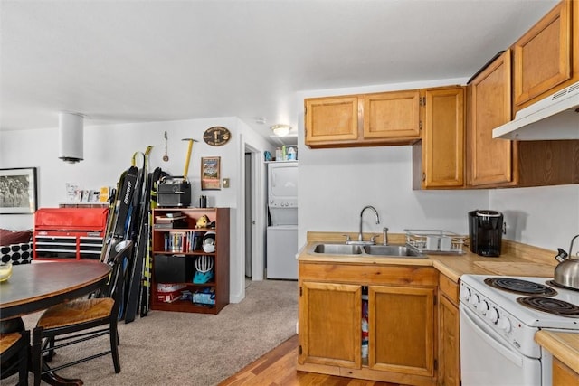 kitchen featuring a sink, white electric range, under cabinet range hood, stacked washing maching and dryer, and light countertops