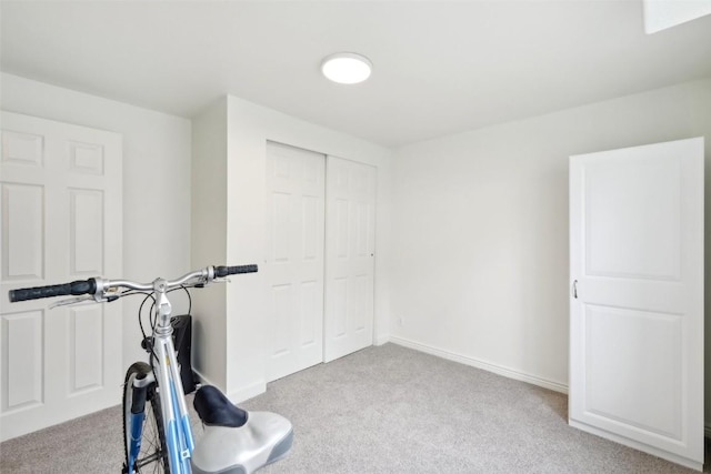 exercise room with baseboards and carpet floors