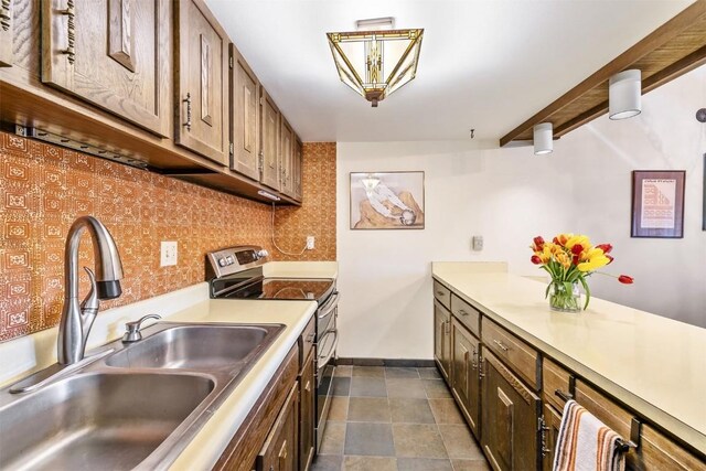 kitchen featuring decorative light fixtures, decorative backsplash, stainless steel electric range oven, and sink