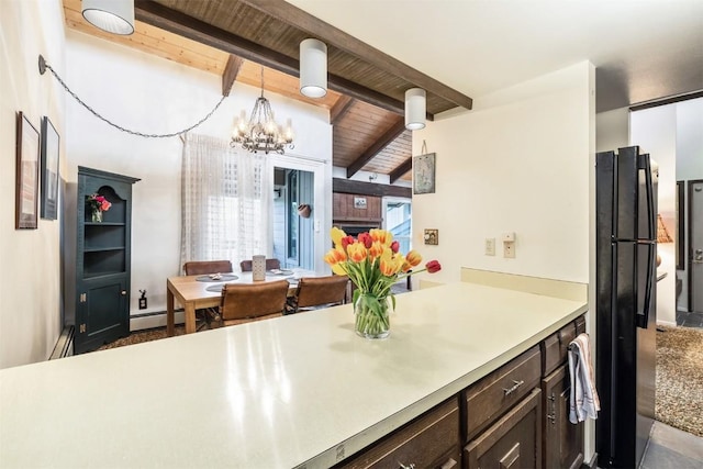 kitchen with black refrigerator, baseboard heating, beam ceiling, an inviting chandelier, and hanging light fixtures