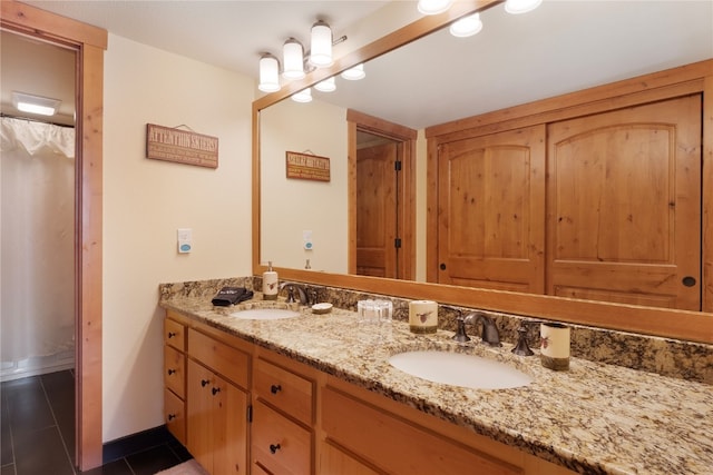 bathroom with double vanity, tile patterned flooring, baseboards, and a sink