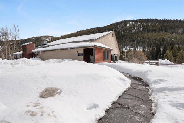 view of snow covered exterior with a wooded view