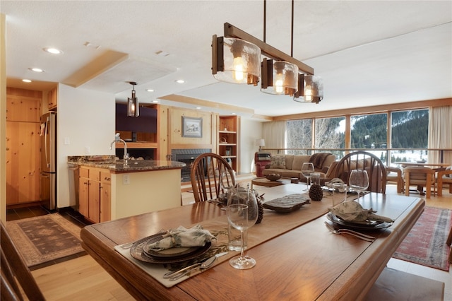 dining space with light wood finished floors, a fireplace, and recessed lighting