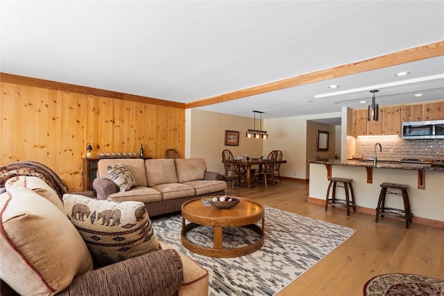 living room featuring baseboards, wooden walls, recessed lighting, and light wood-style floors