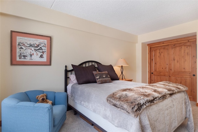 bedroom with a textured ceiling, carpet floors, and a closet