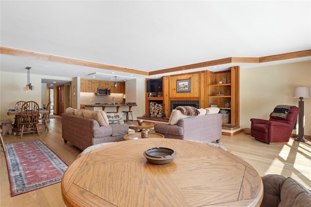 dining area with light wood-type flooring, a fireplace with raised hearth, and recessed lighting