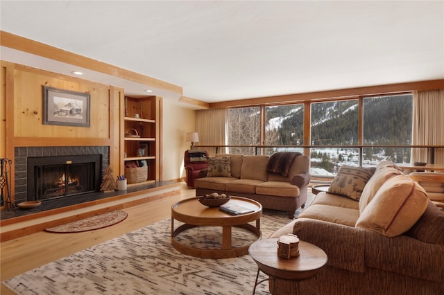 living area featuring recessed lighting, a warm lit fireplace, and wood finished floors