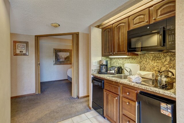 kitchen with sink, black appliances, light stone countertops, a textured ceiling, and light carpet