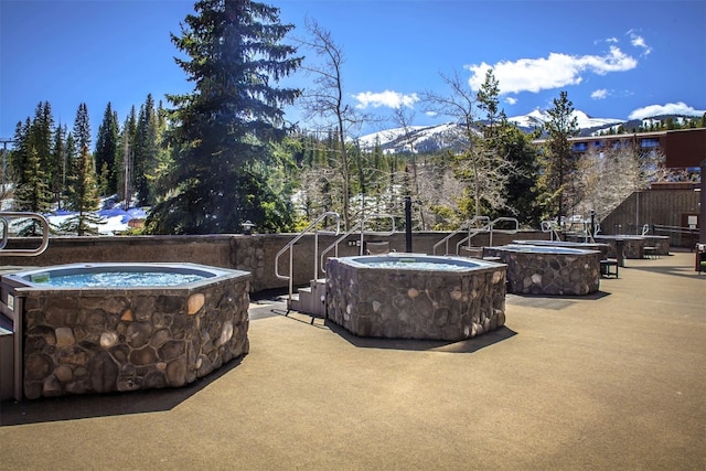 view of patio / terrace featuring a mountain view, a jacuzzi, and an outdoor fire pit