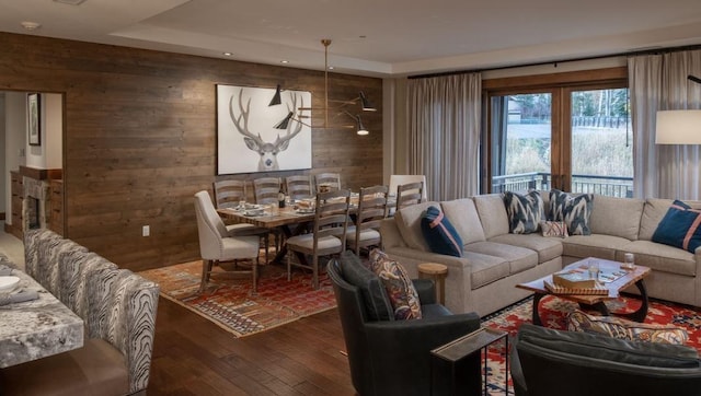 living room featuring dark hardwood / wood-style floors, wooden walls, and a raised ceiling