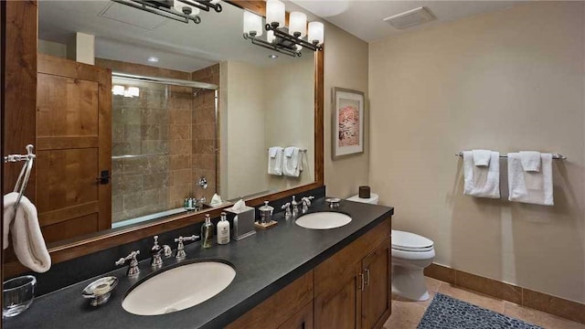 bathroom with a shower with door, vanity, tile patterned floors, and toilet