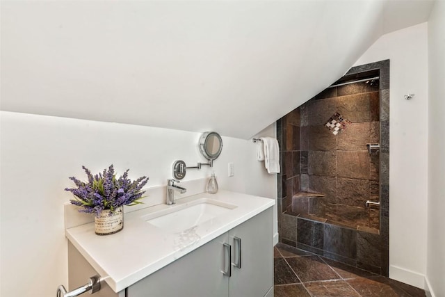 bathroom featuring vaulted ceiling, walk in shower, vanity, and baseboards