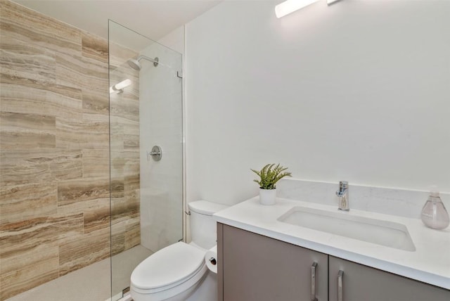 full bath with tiled shower, vanity, and toilet