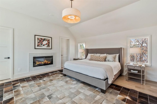 bedroom featuring lofted ceiling, a fireplace, and baseboards