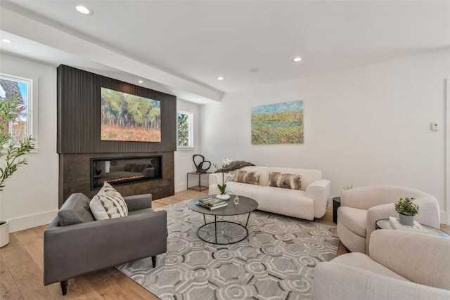 living area with baseboards, a glass covered fireplace, wood finished floors, and recessed lighting