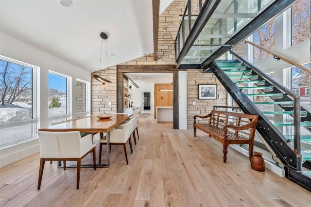 dining room with stairway, light wood-style flooring, and high vaulted ceiling