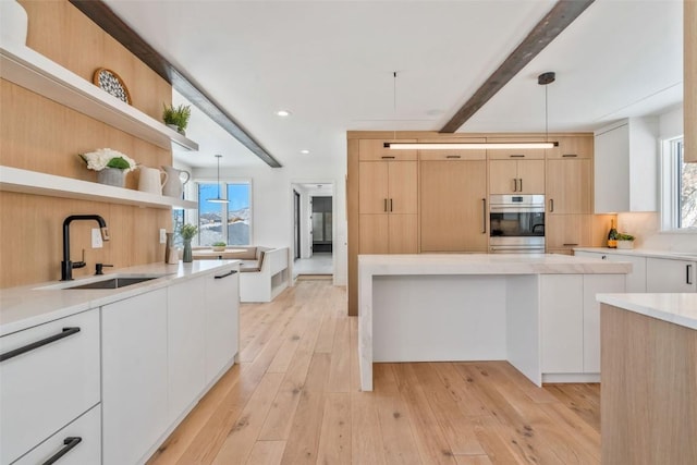 kitchen with stainless steel oven, a sink, open shelves, and modern cabinets