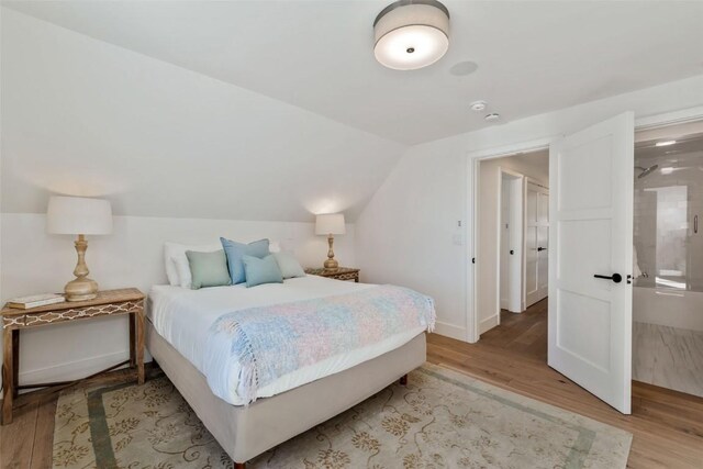 bedroom featuring lofted ceiling, light wood-style flooring, and baseboards