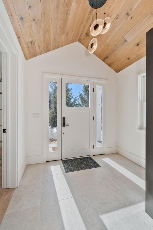 foyer entrance with vaulted ceiling, wooden ceiling, and baseboards