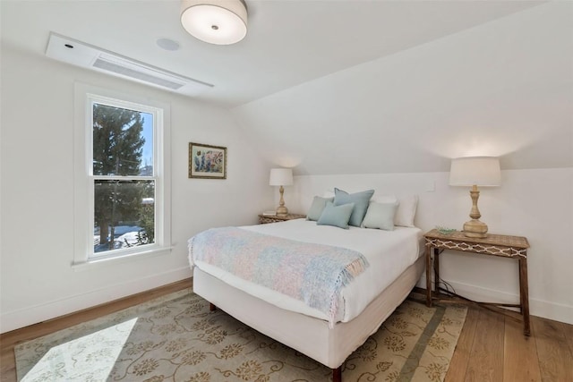 bedroom featuring light wood-type flooring, lofted ceiling, and baseboards