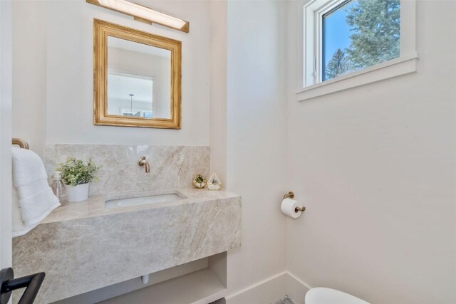 bathroom featuring toilet, vanity, and baseboards