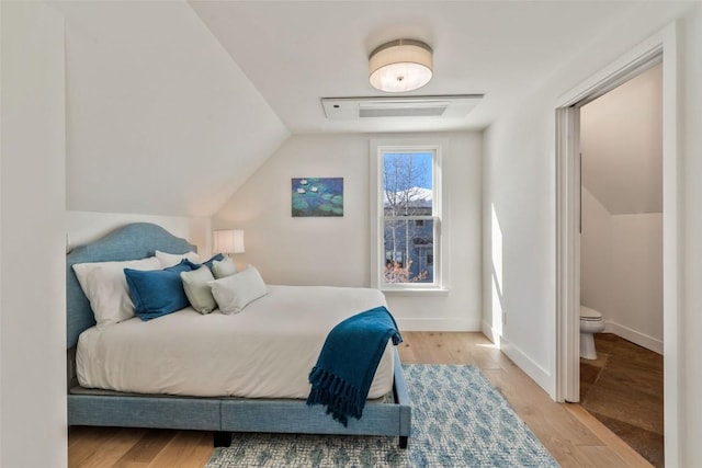 bedroom with lofted ceiling, visible vents, baseboards, and wood finished floors