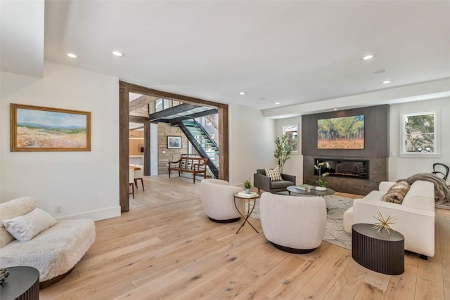 living area featuring light wood finished floors, stairway, a glass covered fireplace, and recessed lighting