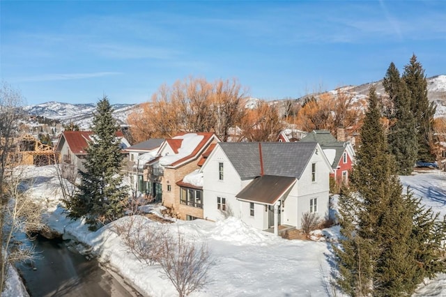 snowy aerial view with a residential view and a mountain view