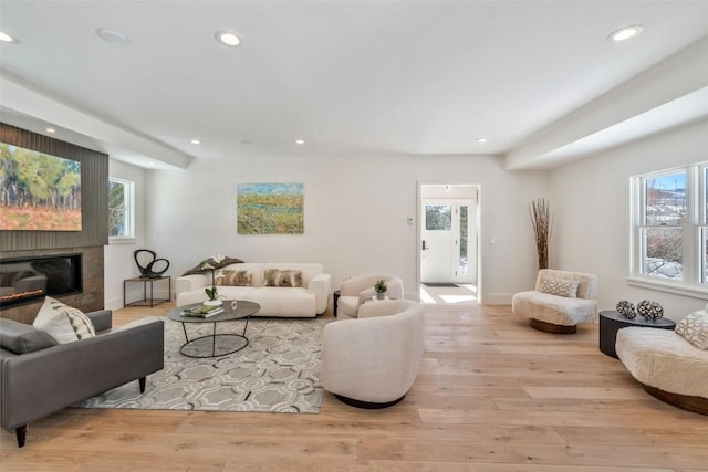 living area with baseboards, a tiled fireplace, wood finished floors, and recessed lighting