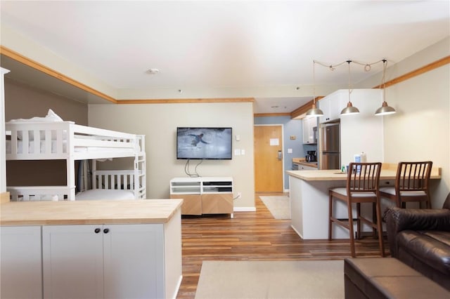 bedroom featuring crown molding, wood finished floors, freestanding refrigerator, and baseboards