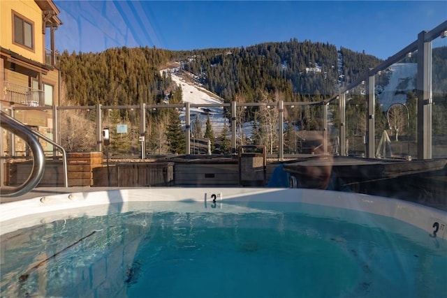 view of pool featuring a forest view, a jacuzzi, and a mountain view