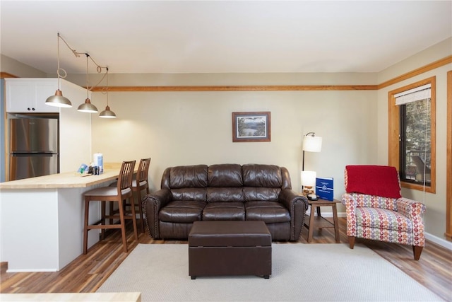 living area with baseboards and wood finished floors