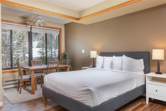 bedroom with a baseboard heating unit and wood finished floors