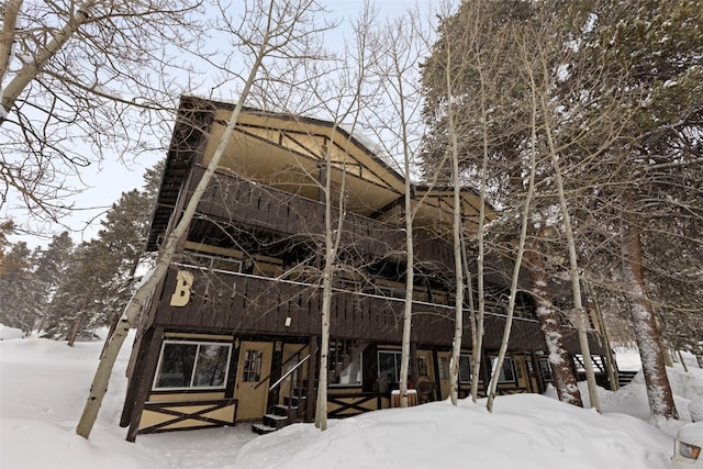 snow covered back of property featuring a balcony