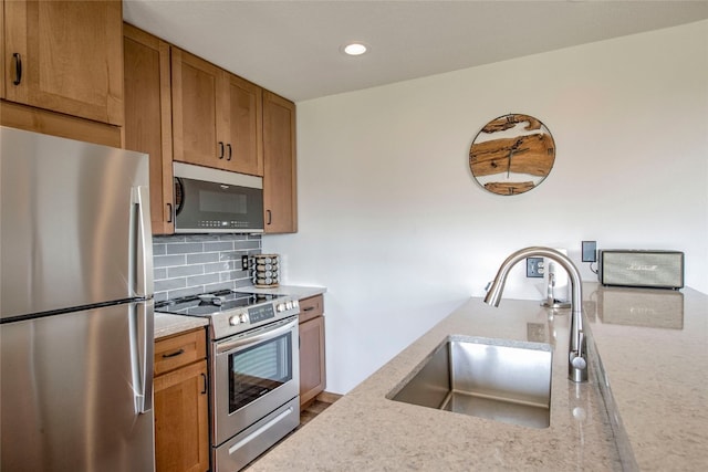 kitchen featuring sink, decorative backsplash, stainless steel appliances, and light stone countertops