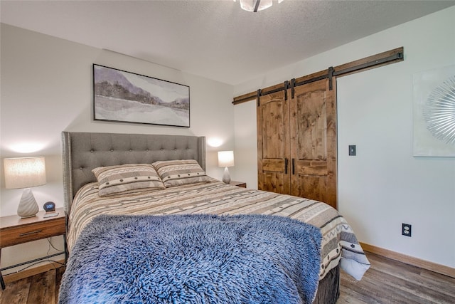 bedroom with a barn door, hardwood / wood-style floors, and a textured ceiling