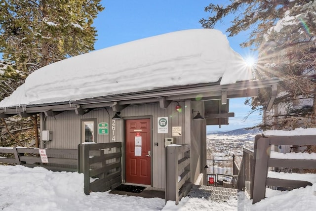 snow covered property entrance with fence