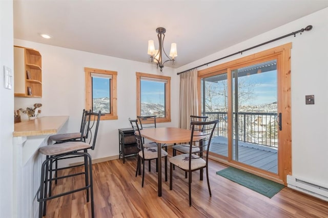 dining space with a baseboard radiator, a notable chandelier, baseboards, and wood finished floors