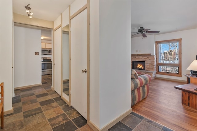 hallway featuring stone finish flooring and baseboards